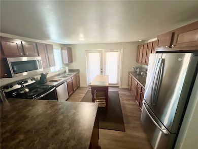 Kitchen with stainless steel appliances, dark wood-style floors, island and French doors