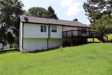 Back of property featuring a deck, a yard, a chimney, and stairway
