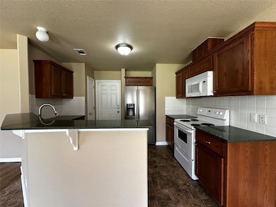 Kitchen with white appliances, a peninsula, dark 
