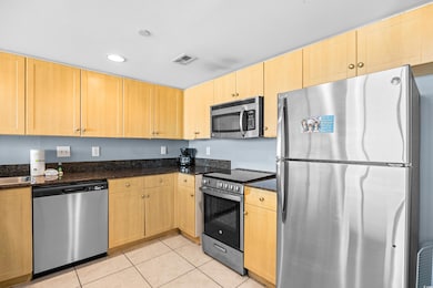 Kitchen with dark stone countertops, light brown c
