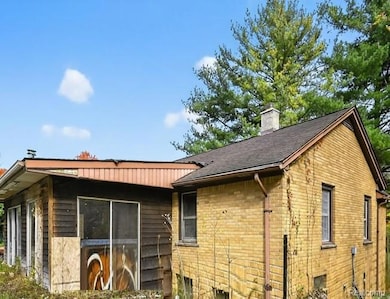 View of home's exterior featuring brick siding, a chimney, and a shingled roof