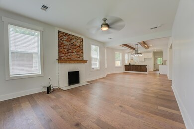 Unfurnished living room featuring a brick fireplace, a ceiling fan, light wood-style flooring, and baseboards