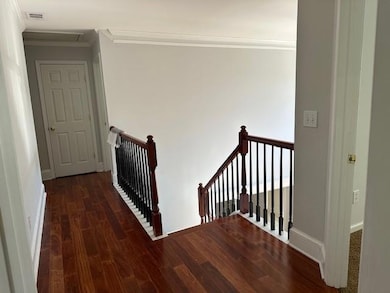 Corridor with an upstairs landing, ornamental molding, and dark wood-style floors