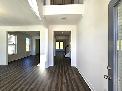 Entryway featuring dark wood-style floors, crown molding, and stairway