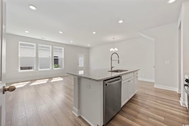 Kitchen with light stone counters, dishwasher, recessed lighting, an island with sink, and white cabinetry