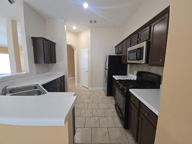 Kitchen featuring black appliances, arched walkways, dark brown cabinetry, light countertops, and backsplash