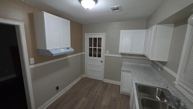 Kitchen featuring white cabinetry and wood finished floors
