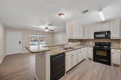 Kitchen featuring kitchen peninsula, sink, black appliances, and light hardwood / wood-style flooring