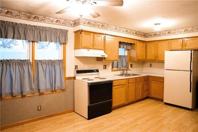 Kitchen with white appliances, sink, ceiling fan, light wood-type flooring, and a textured ceiling