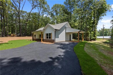 Modern inspired farmhouse with asphalt driveway, a front yard, roof with shingles, and an attached carport