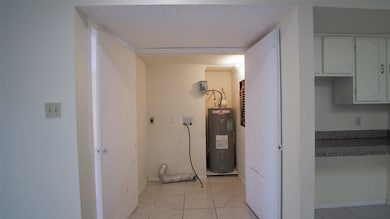 The utility room is conveniently located inside the house, situated between the primary bedroom and the kitchen nook.