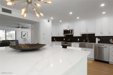 Kitchen featuring stainless steel appliances, tasteful backsplash, white cabinets, recessed lighting, and crown molding