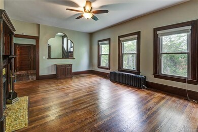 Living room with abundant natural light, with view into central hallway and staircase.