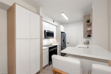 Kitchen with stainless steel microwave, electric stove, refrigerator with ice dispenser, a peninsula, and open shelves
