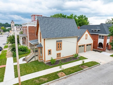 View of front facade with roof with shingles, board and batten siding, driveway, and a front yard