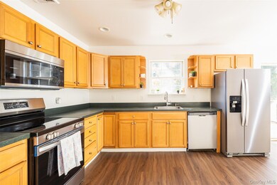 Kitchen with appliances with stainless steel finishes, dark wood-style flooring, open shelves, dark countertops, and recessed lighting