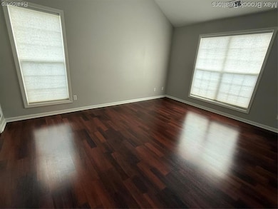Spare room featuring dark wood finished floors and lofted ceiling