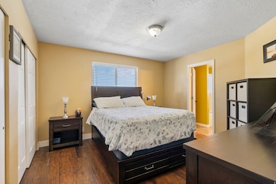 Bedroom with dark wood finished floors, a textured ceiling, a closet, and an office area