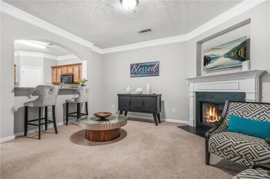 Living area with carpet flooring, arched walkways, a fireplace with flush hearth, crown molding, and baseboards