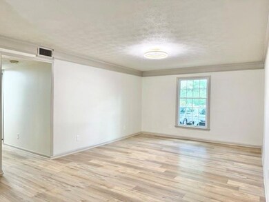 Empty room featuring ornamental molding, light wood-type flooring, and a textured ceiling