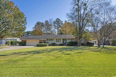 Ranch-style house with a front lawn, driveway, a garage, brick siding, and crawl space