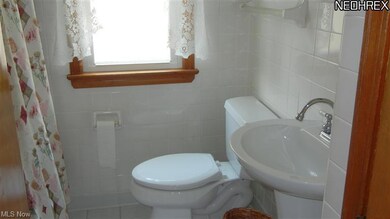 Remodeled bath with pedestal sink, updated light fixture, and ceramic tile flooring.
