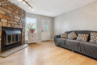 Living area with track lighting, a large fireplace, baseboards, and wood finished floors