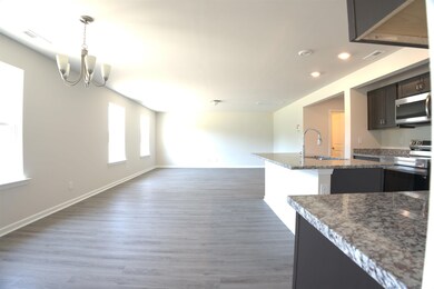 Kitchen with appliances with stainless steel finishes, a chandelier, open floor plan, recessed lighting, and wood finished floors