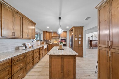 Kitchen featuring a center island, pendant lighting, backsplash, and custom range hood