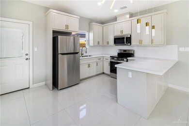 Kitchen featuring stainless steel appliances, a sink, a peninsula, light countertops, and baseboards