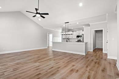 Unfurnished living room with ceiling fan, sink, cr