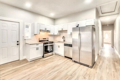 Kitchen with white cabinetry, appliances with stai