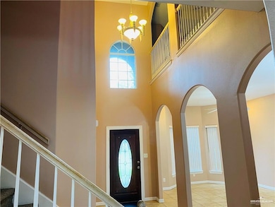 Foyer with a towering ceiling, stairs, arched walkways, a chandelier, and light tile patterned floors