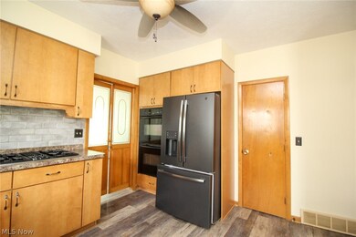 Kitchen with tasteful backsplash, dark hardwood / wood-style flooring, appliances with stainless steel finishes, and ceiling fan