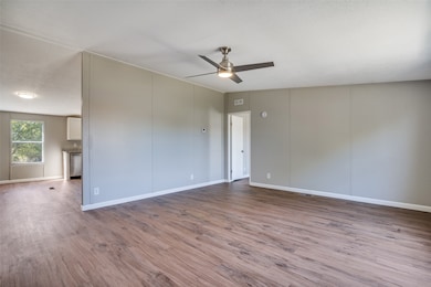 Unfurnished room featuring wood finished floors, ceiling fan, and a decorative wall