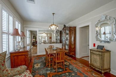 Dining room with antique chandelier, wood floors & plantation shutters.