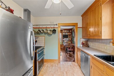 Kitchen with appliances with stainless steel finishes, light laminate floors, ceiling fan, and tasteful backsplash