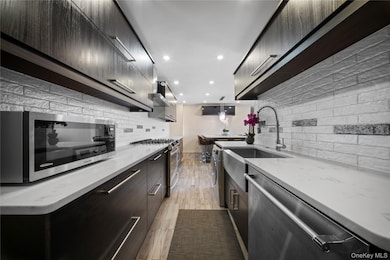 Kitchen with modern cabinets, appliances with stainless steel finishes, light stone countertops, recessed lighting, and light wood-style floors