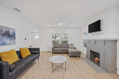 Living area featuring light wood-style flooring, recessed lighting, ceiling fan, and a fireplace