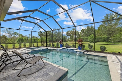 Sparkling pool and spa with a centered fire bowl accent overlooking the lush backyard