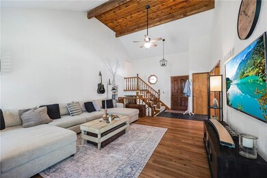 Living area with beamed ceiling, dark wood-style floors, ceiling fan, stairs, and high vaulted ceiling