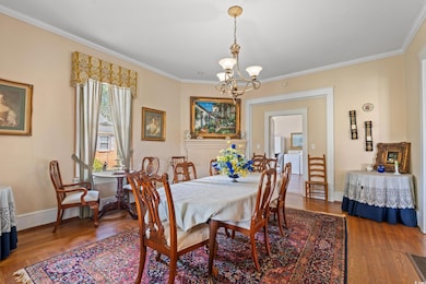 Dining room featuring a chandelier, wood finished floors, crown molding, and washing machine and clothes dryer