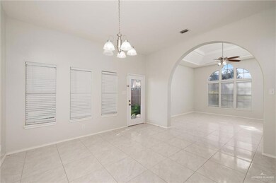 Empty room featuring arched walkways, light tile patterned flooring, a ceiling fan, and a chandelier