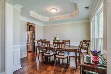 The Formal Dining Room displays a subtle elegance with crown molding, hardwood flooring, a chair rail with wainscot, and an octagonal trey ceiling. Entertain family and friends while overlooking the spacious front yard and common area beyond.