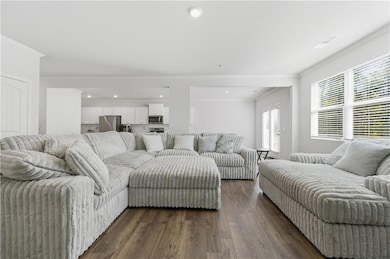 Living area featuring ornamental molding, dark wood-style flooring, and recessed lighting