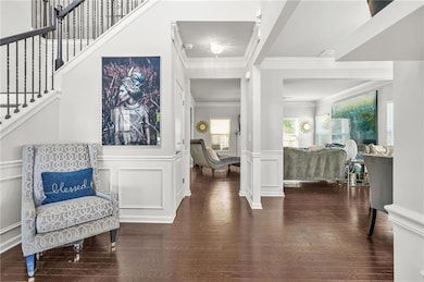 Entryway featuring stairway, a decorative wall, decorative columns, ornamental molding, and wainscoting