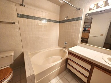 Full bathroom with a textured wall, toilet, tile p