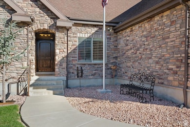 Doorway to property with stone siding and a shingled roof