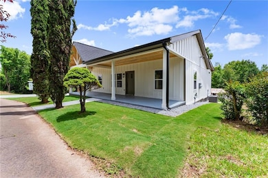 View of front of house with board and batten siding, a front yard, a patio, and a shingled roof