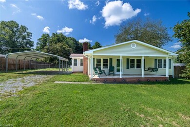 Front View: Here we can see the covered front porch, the green grass and mature trees in the backyard, the sidewalk up to the front porch. A gravel driveway is to the left side with a 2-car detached carport. Now picture yourself relaxing on the front porch with a cool beverage and good company.